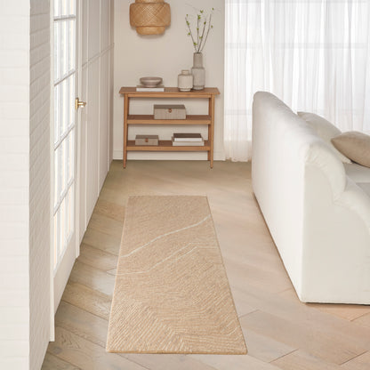 Neutral living room featuring a long beige woven runner rug, light wood console table, white sofa and sheer curtains.