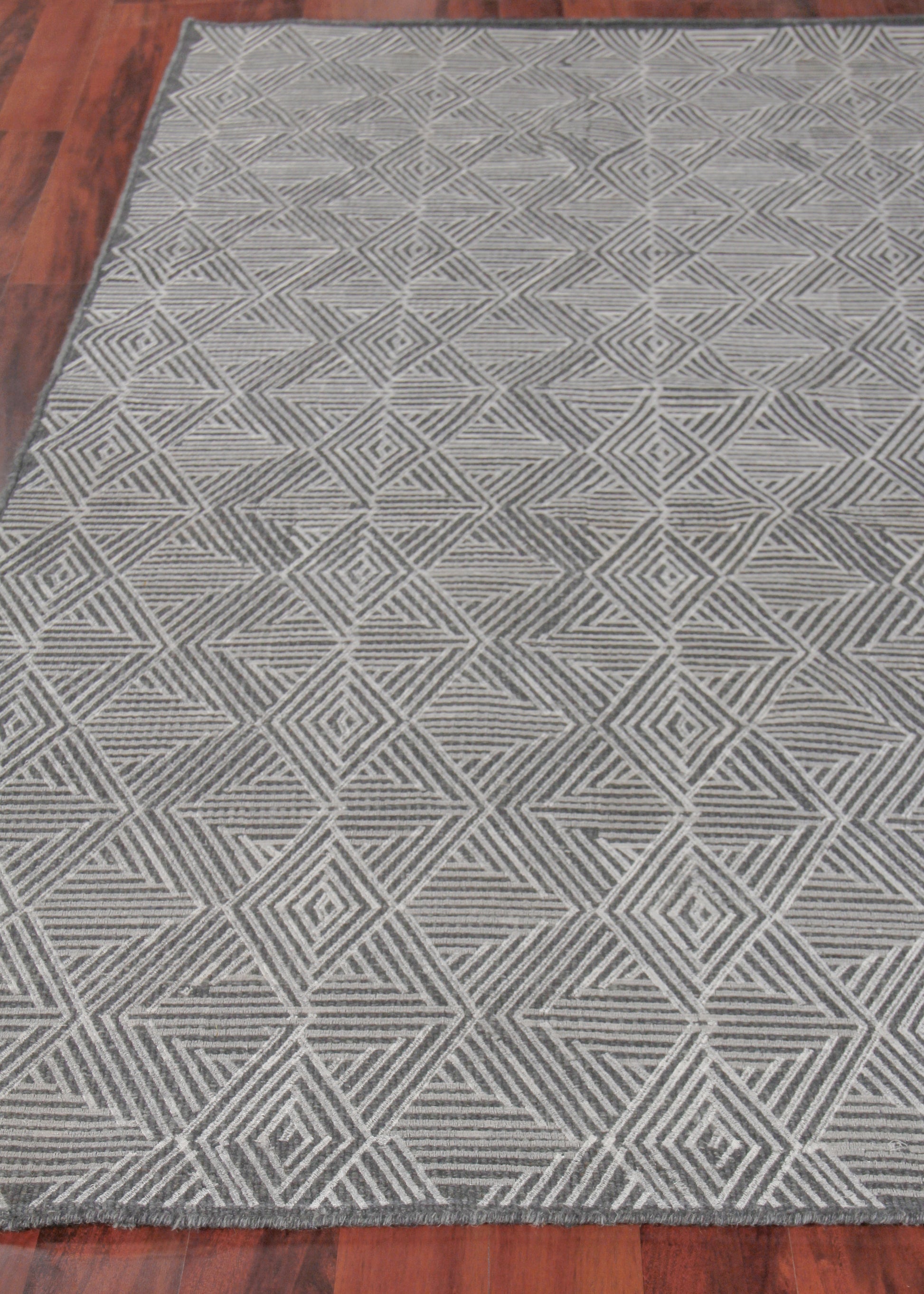 Grey geometric area rug with interlocking diamond and triangle pattern; modern neutral rectangle for living room.