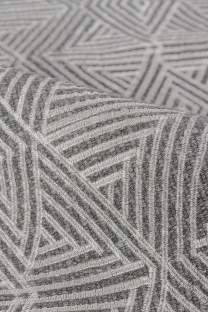 Grey geometric flat-weave rug with white linear chevron and triangle patterns; soft woven texture.