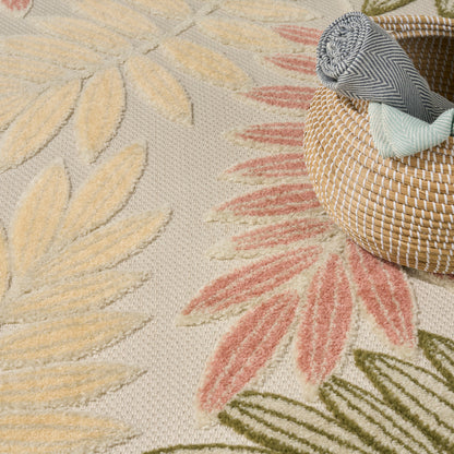 Textured rug with yellow, pink, and green palm leaf patterns beside a woven straw basket holding rolled blankets.