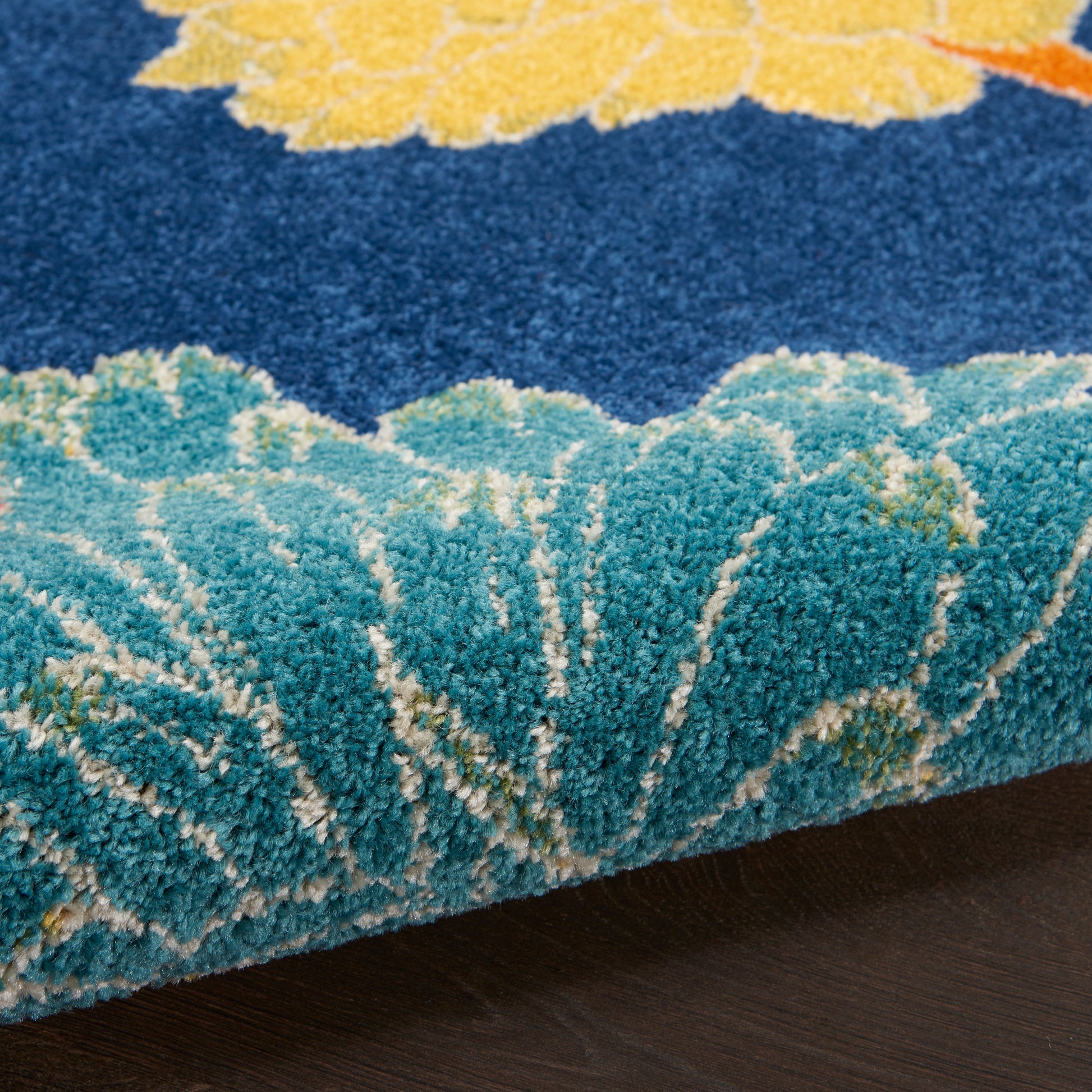 Thick plush area rug with teal and turquoise waves on a navy blue field; yellow floral accent, soft shag texture.