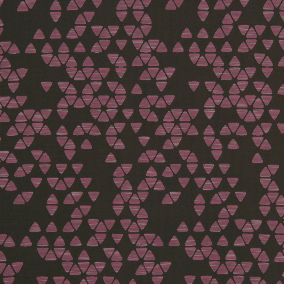 Dark charcoal fabric with small pink triangular clusters forming circular motifs in a geometric, repeating pattern.