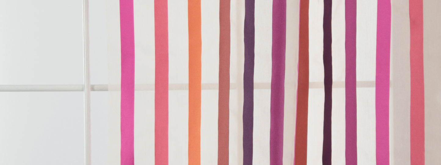Vertical color-striped drapery fabric in pink, orange, purple and brown tones.