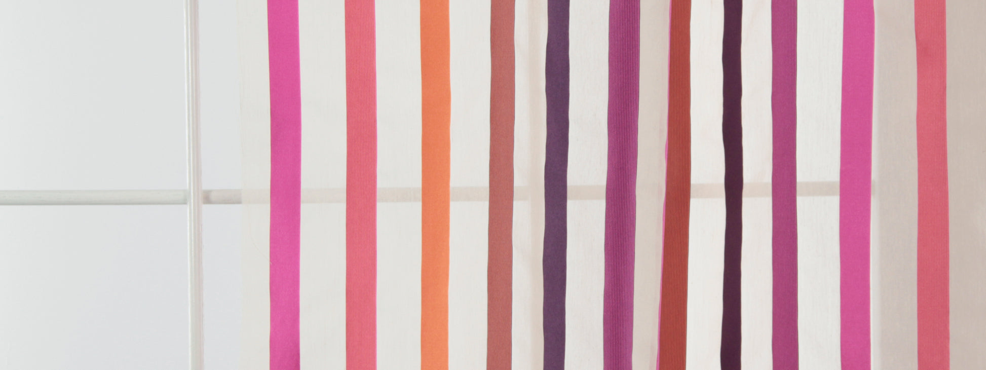 Vertical color-striped drapery fabric in pink, orange, purple and brown tones.
