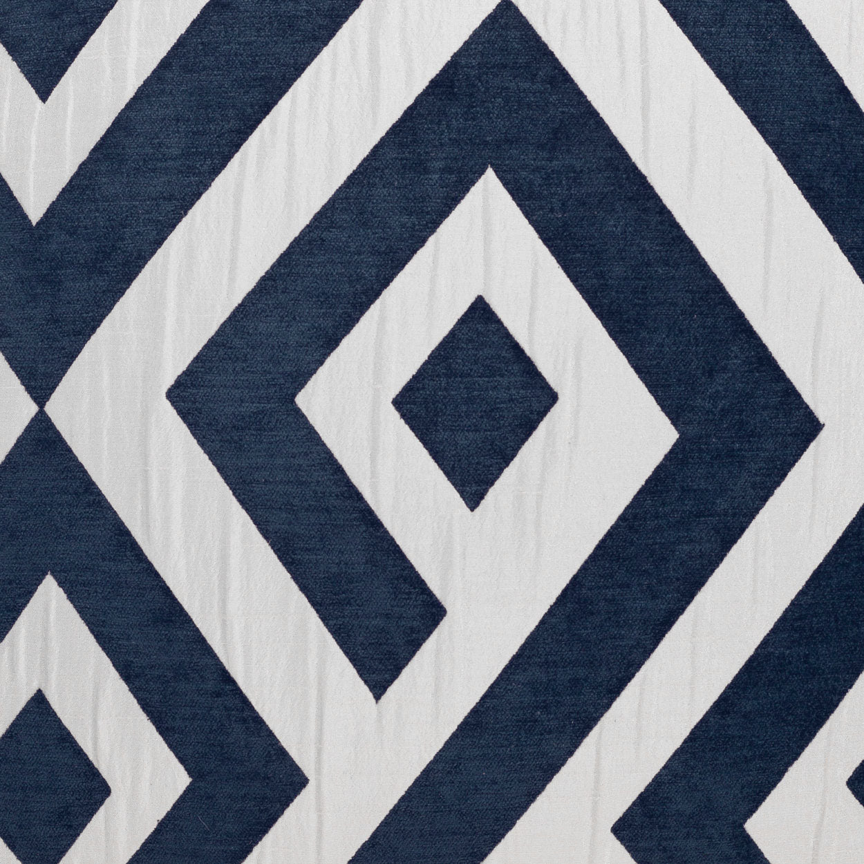 Navy blue and white diamond-pattern fabric on a pillow with concentric diamonds; bold geometric, nautical-inspired design.