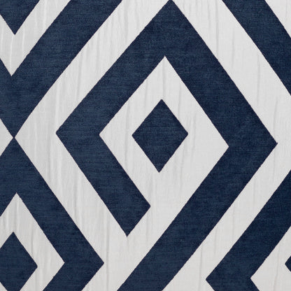 Navy blue and white diamond-pattern fabric on a pillow with concentric diamonds; bold geometric, nautical-inspired design.