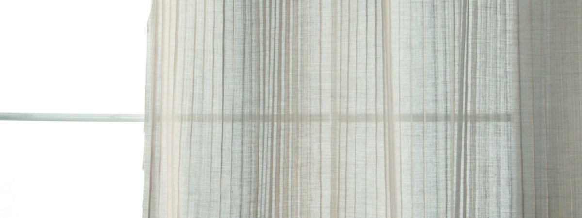 Light gray striped linen drapery curtains over a window, softly filtering daylight.