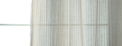 Light gray striped linen drapery curtains over a window, softly filtering daylight.