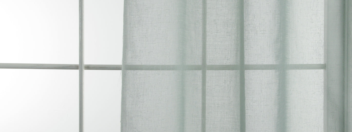 Aquamarine sheer drapery panel in front of a window with grid panes, diffusing soft daylight.