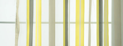 Vertical ribbon curtain strands in yellow, gray and cream, a modern window decor piece.
