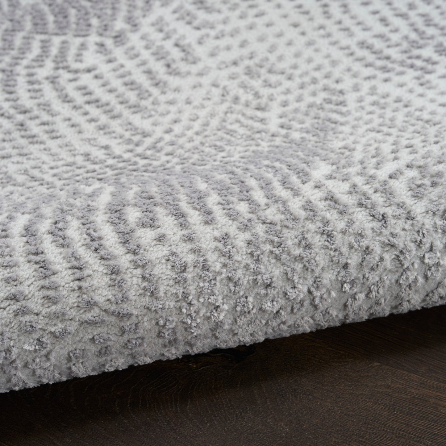 Soft light gray plush rug with textured pattern and dense pile on dark wood floor.