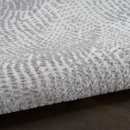 Soft light gray plush rug with textured pattern and dense pile on dark wood floor.