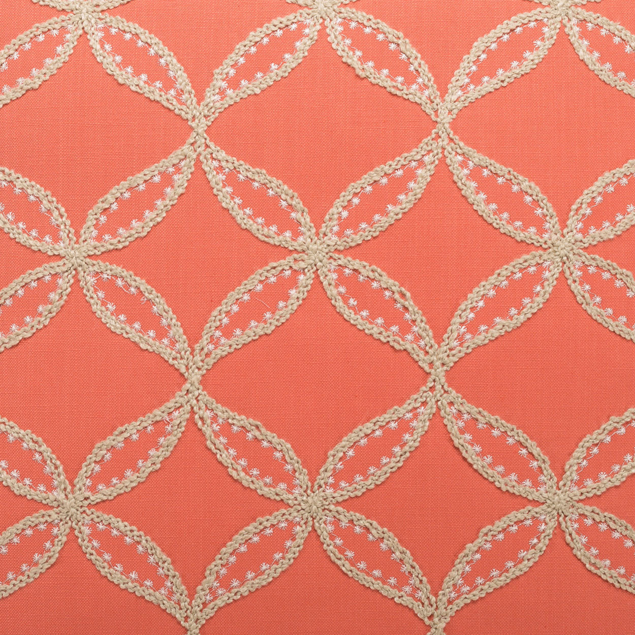 Pillow in coral fabric with cream crochet lattice of interlocking circles, edged with floral scalloped trim.
