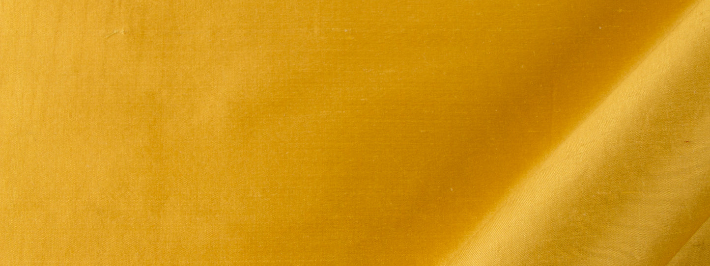 Gold silk drapery fabric with a diagonal crease and a glossy, shimmering finish.
