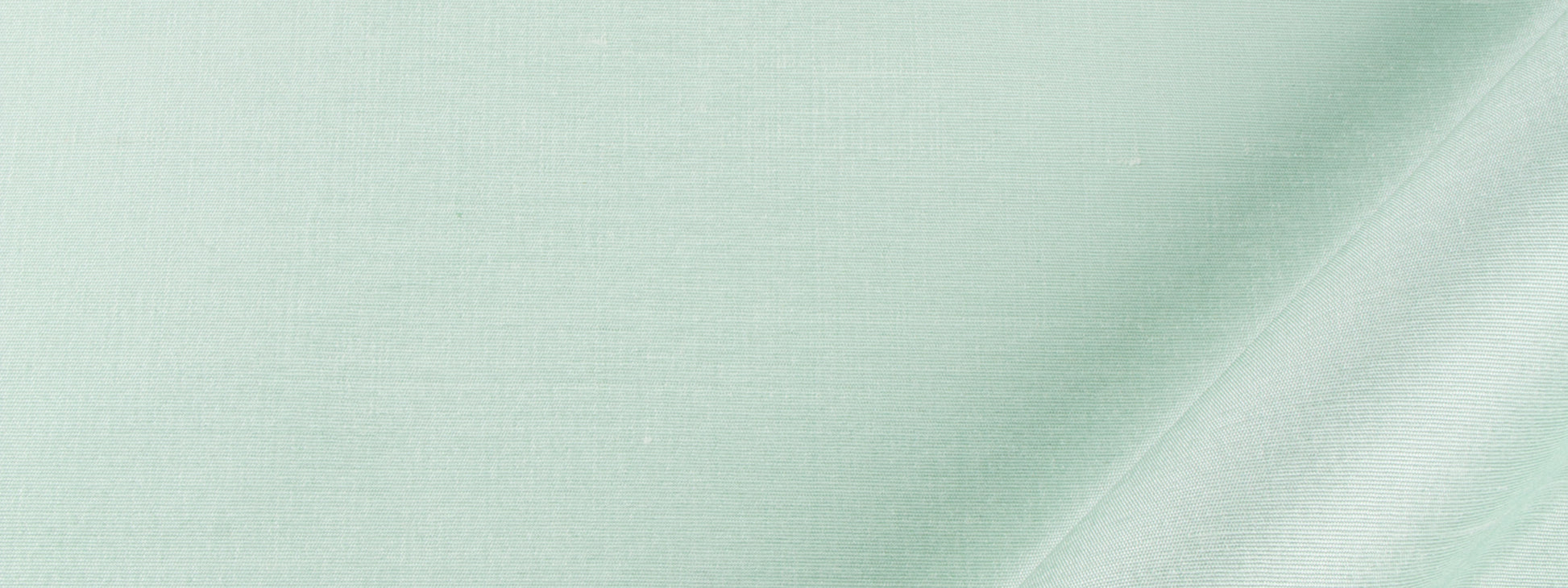 Mint green drapery fabric with a subtle weave texture and a diagonal seam or fold across the material.