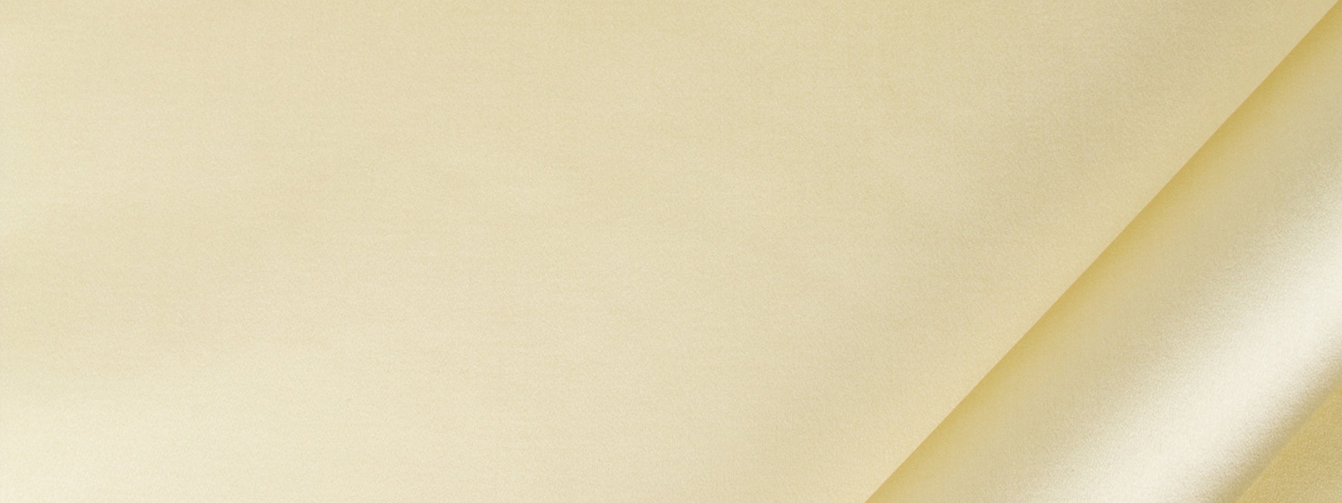 Pale yellow satin drapery fabric with diagonal fold and subtle texture.
