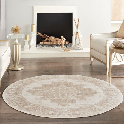 Round beige rug with a soft distressed ivory medallion pattern in a light, neutral living room.