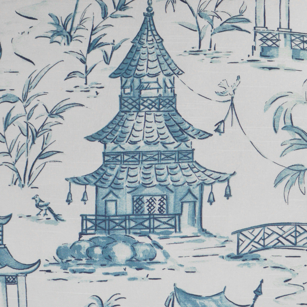 Blue pagoda temple chinoiserie pattern on white fabric with bamboo and bridge motifs.