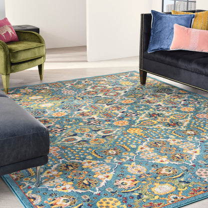 Ornate blue teal patterned area rug over light wood floor, with green velvet armchair and black sofa with colorful cushions.