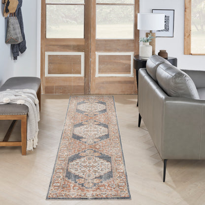 Long oriental runner rug with cream, blue & rust medallions, laid between a gray sofa and bench in a cozy living room.