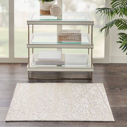 Beige rug on dark wood floor with yarn ball, wooden box, and stacked books nearby; size 2' x 3'.