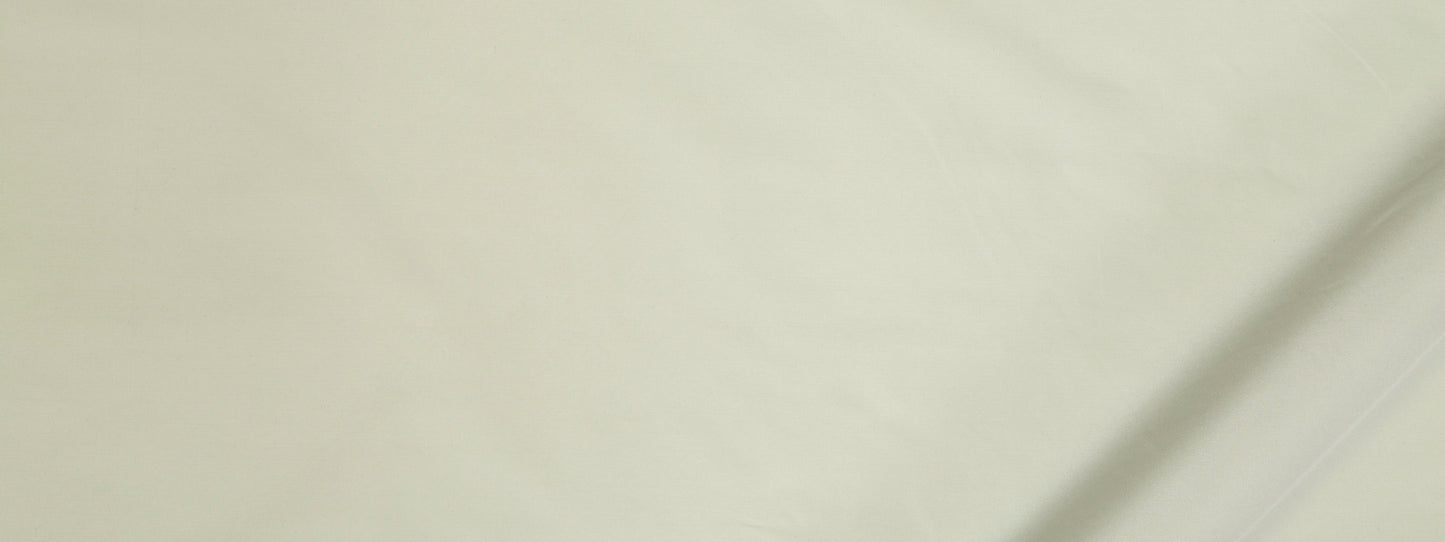 Close-up of pale cream fabric with subtle texture and a visible seam along the edge.