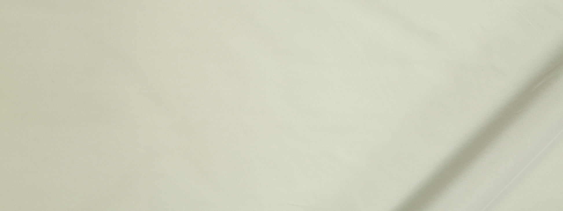 Close-up of pale cream fabric with subtle texture and a visible seam along the edge.