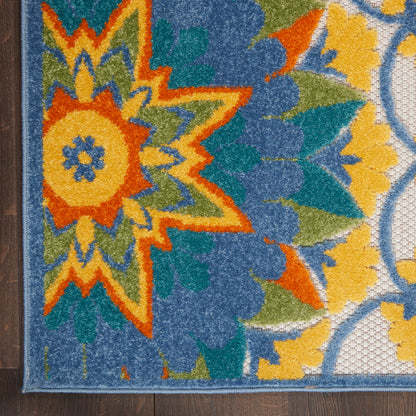 Close-up of a vibrant floral rug with an orange-yellow starburst center, blue and green petals, textured pile, and a blue border.