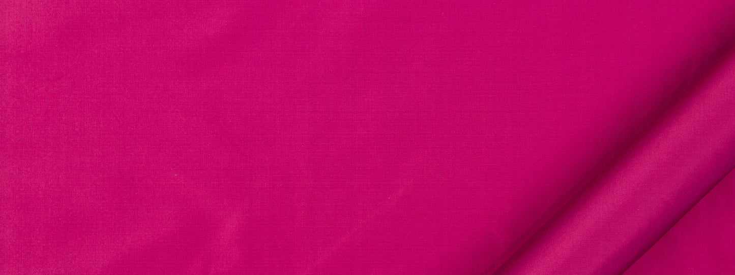 Close-up of vivid magenta fabric with a folded corner, smooth textile texture.