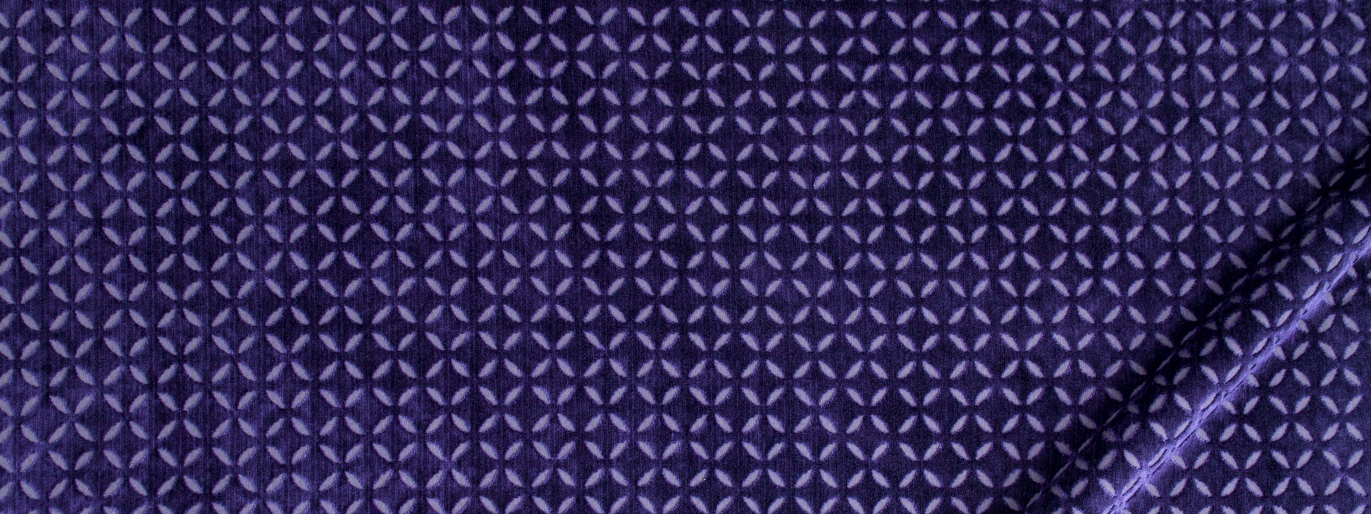 Deep purple fabric with tiny light-purple star-like geometric pattern, folded edge on the right.