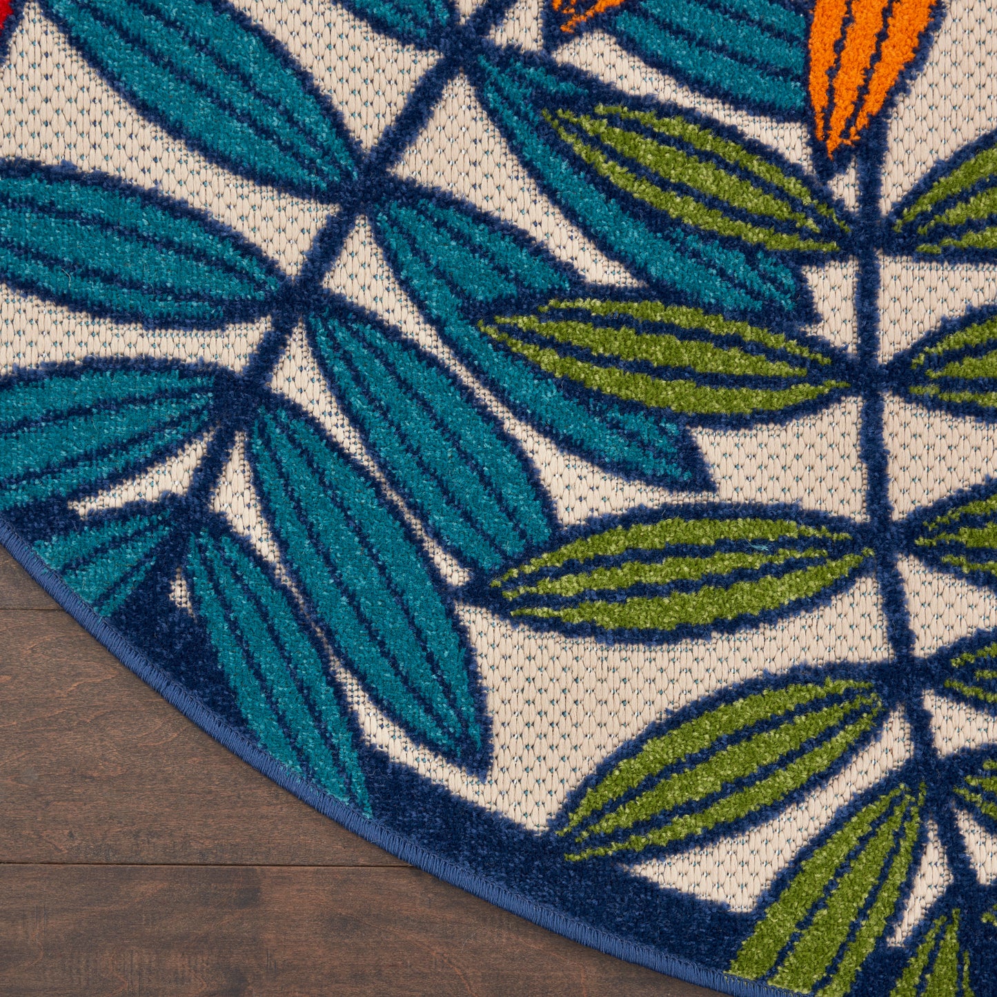 Teal and navy leaf-pattern rug edge on dark wood floor with a large gray blurred panel overlay.