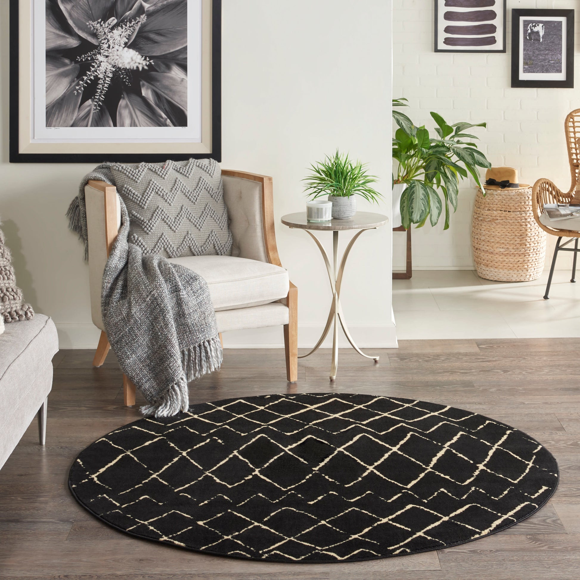 Round black rug with white lattice pattern in a cozy modern living room beside beige armchair and round table with plants.