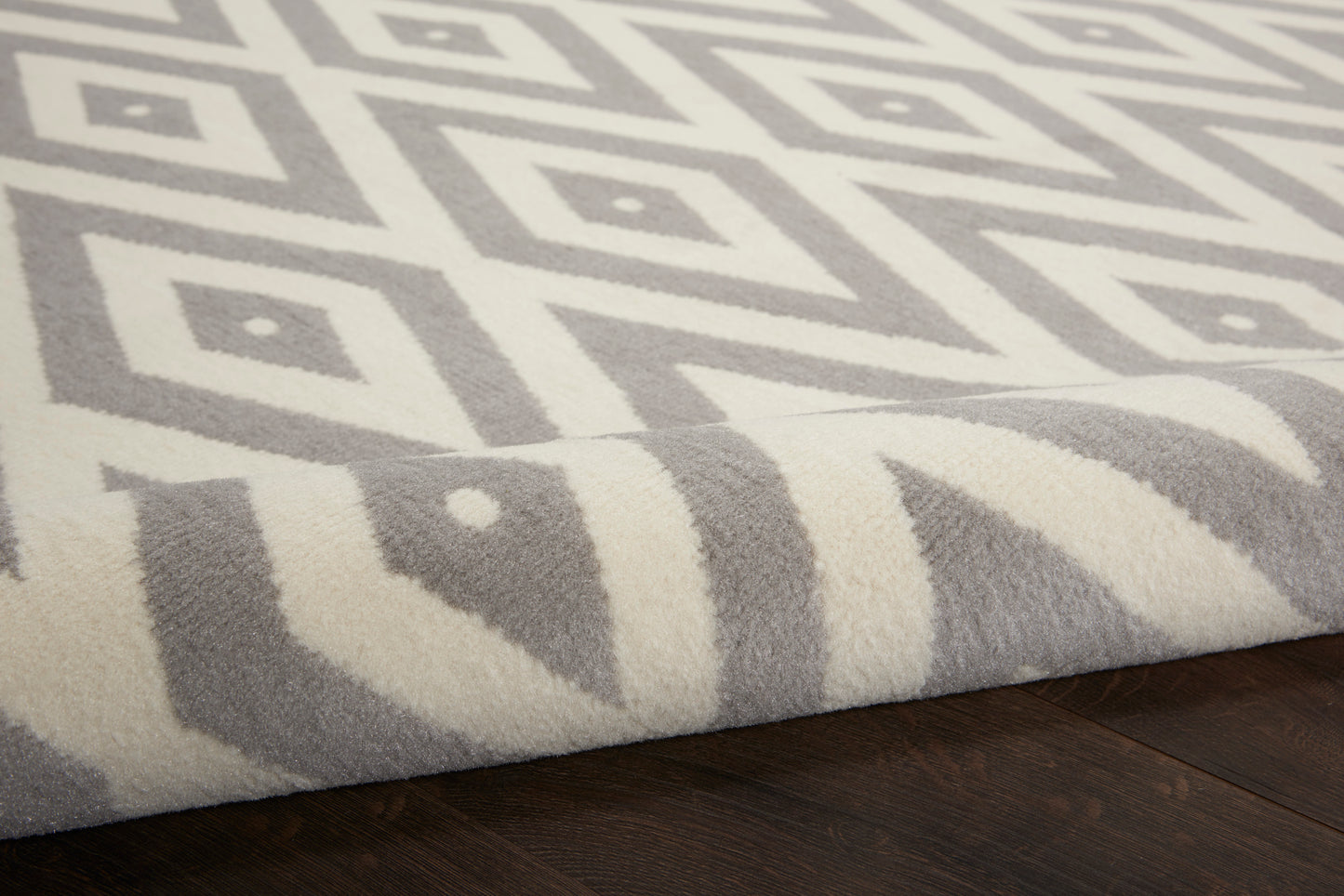 Ivory & gray geometric diamond area rug with plush texture on dark wooden floor.