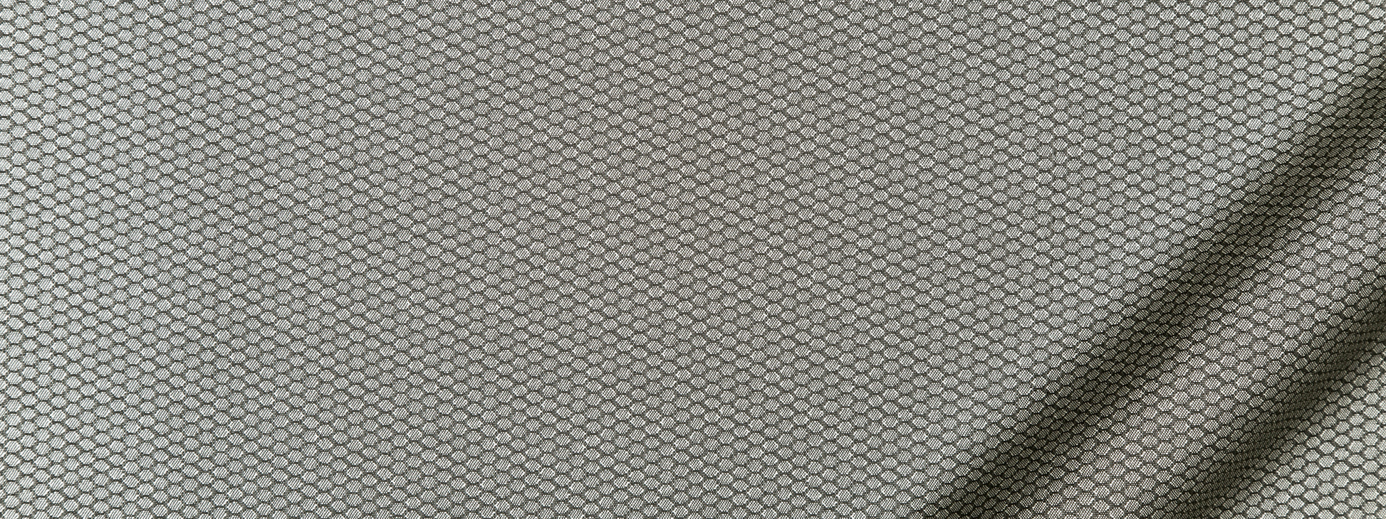 Close-up of light gray upholstery fabric with a subtle honeycomb hexagonal weave pattern.