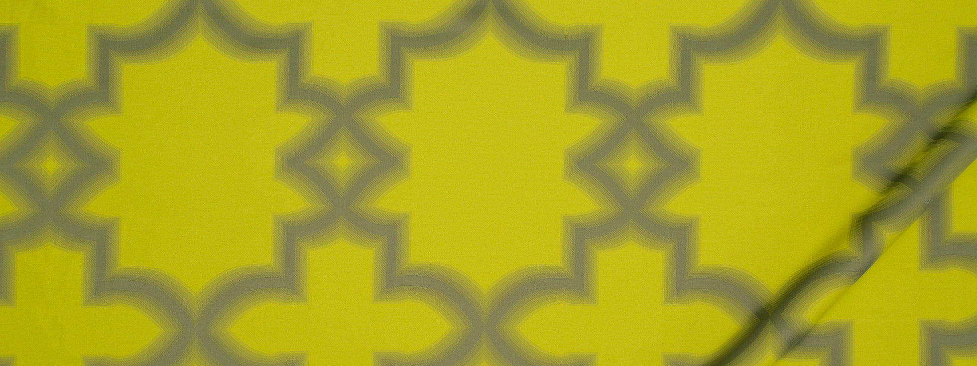 Vibrant citron geometric lattice with interlocking quatrefoil shapes; bold pattern suitable for wallpaper or fabric.