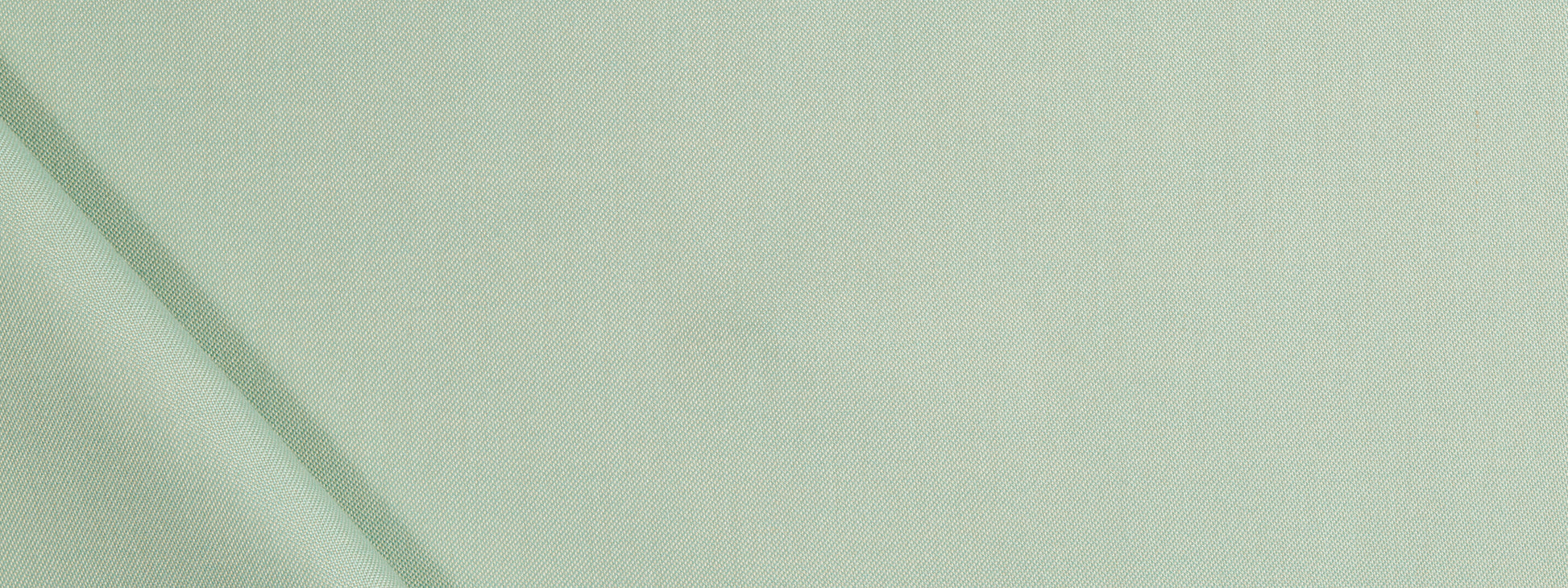 Close-up of pale sage-green upholstery fabric with soft folds and subtle diagonal seam lines.
