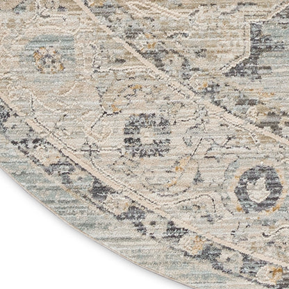 Round distressed oriental rug in beige, ivory, pale blue and gray with arabesque floral motif.