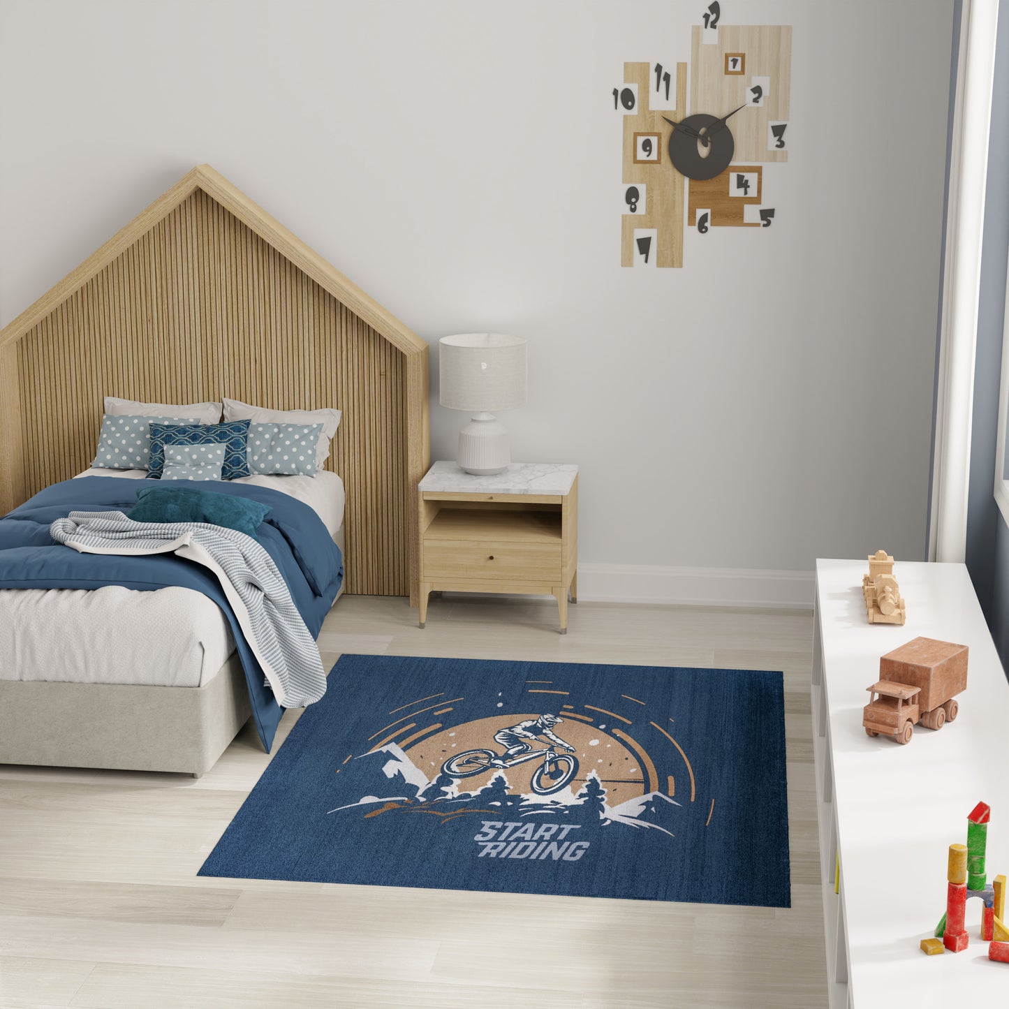 Bedroom with a house-shaped wooden headboard, blue bedding, white nightstand, and a blue bike rug saying Start Riding.