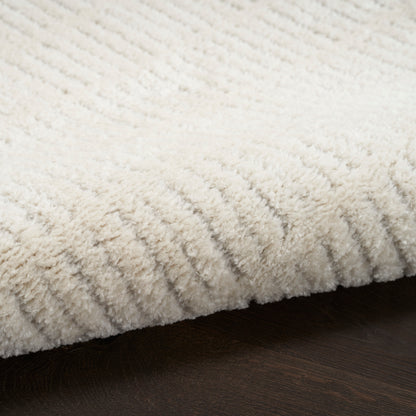 Cream shag rug with thick plush pile on dark wood floor, cozy and soft.