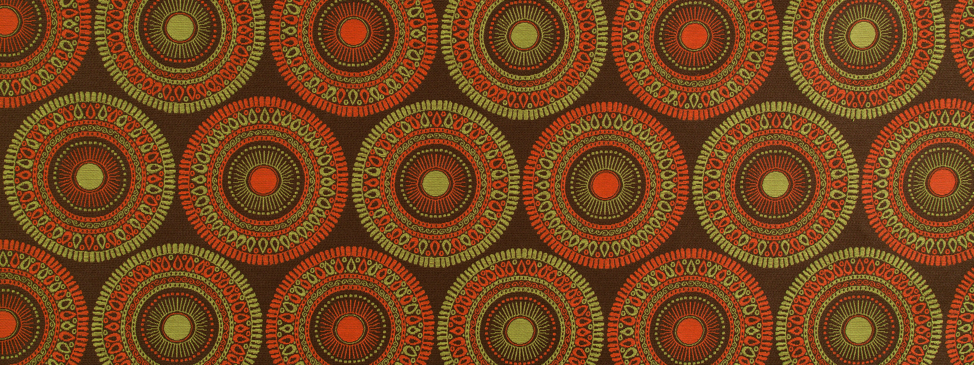 Bohemian circular medallion textile print in orange and olive on a dark brown background; repeating upholstery fabric pattern.