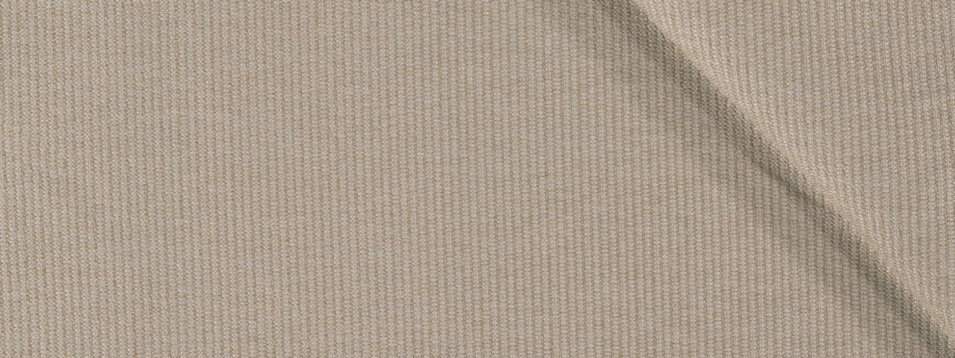 Close-up of beige ribbed fabric with a diagonal crease and fine knit texture.