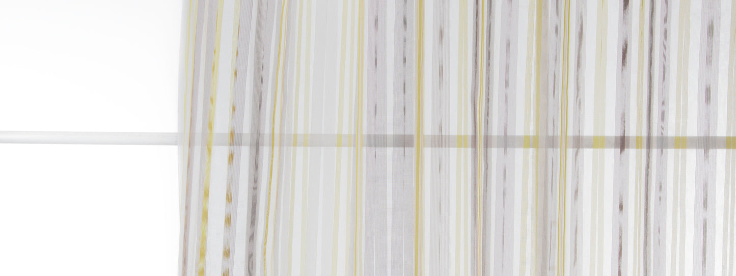 Vertical striped sheer curtain in white, gray & pale yellow with flowing folds by a window.