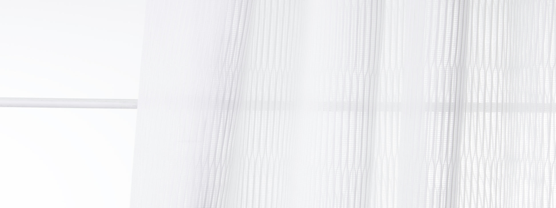 Bone-colored sheer voile curtains with soft vertical folds, airy light-filtering window drape.