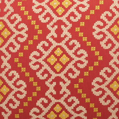 Red fabric with cream scrolling geometric motifs and gold diamond centers in a repeating kilim-like pattern.