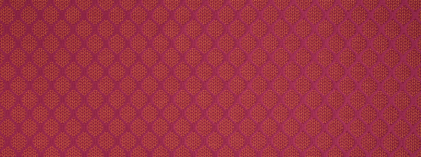 Maroon fabric pattern with small orange lattice motifs in a repeating geometric damask design.