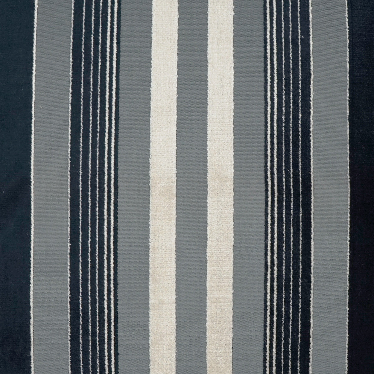 Vertical striped fabric rug in navy, gray, and ivory with bold and slim stripes.