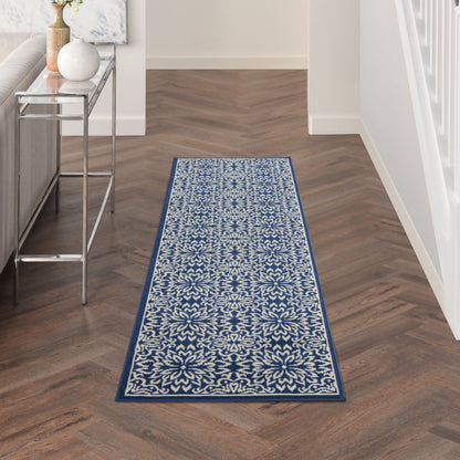 Blue and white floral patterned runner rug with ornate medallion border in a wood-floored hallway.