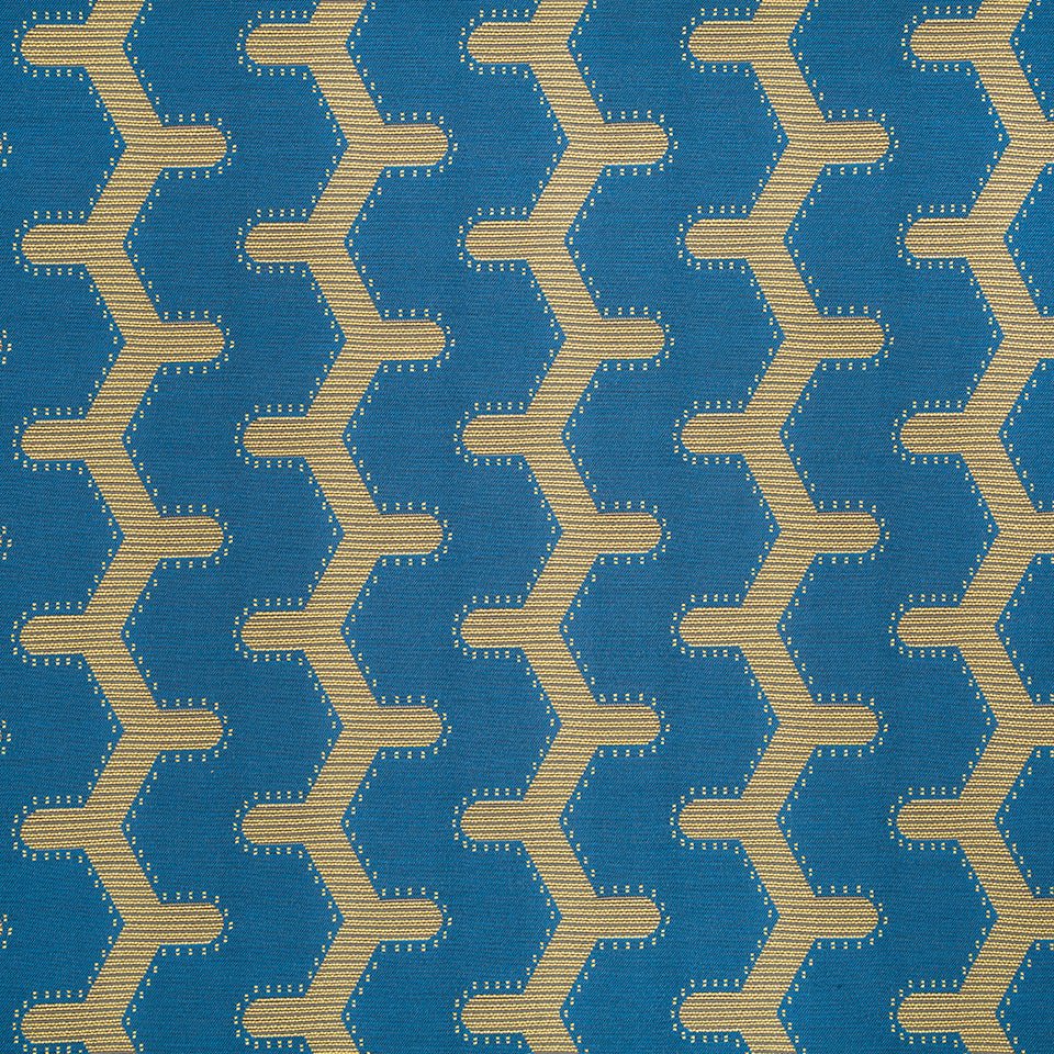 Blue woven fabric with repeating beige zigzag chain pattern; geometric chevron upholstery textile.