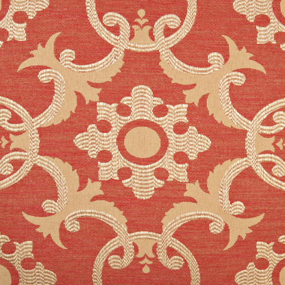 Red damask pillow with cream-beige ornate medallion and scrolling motifs in a repeating symmetrical pattern.