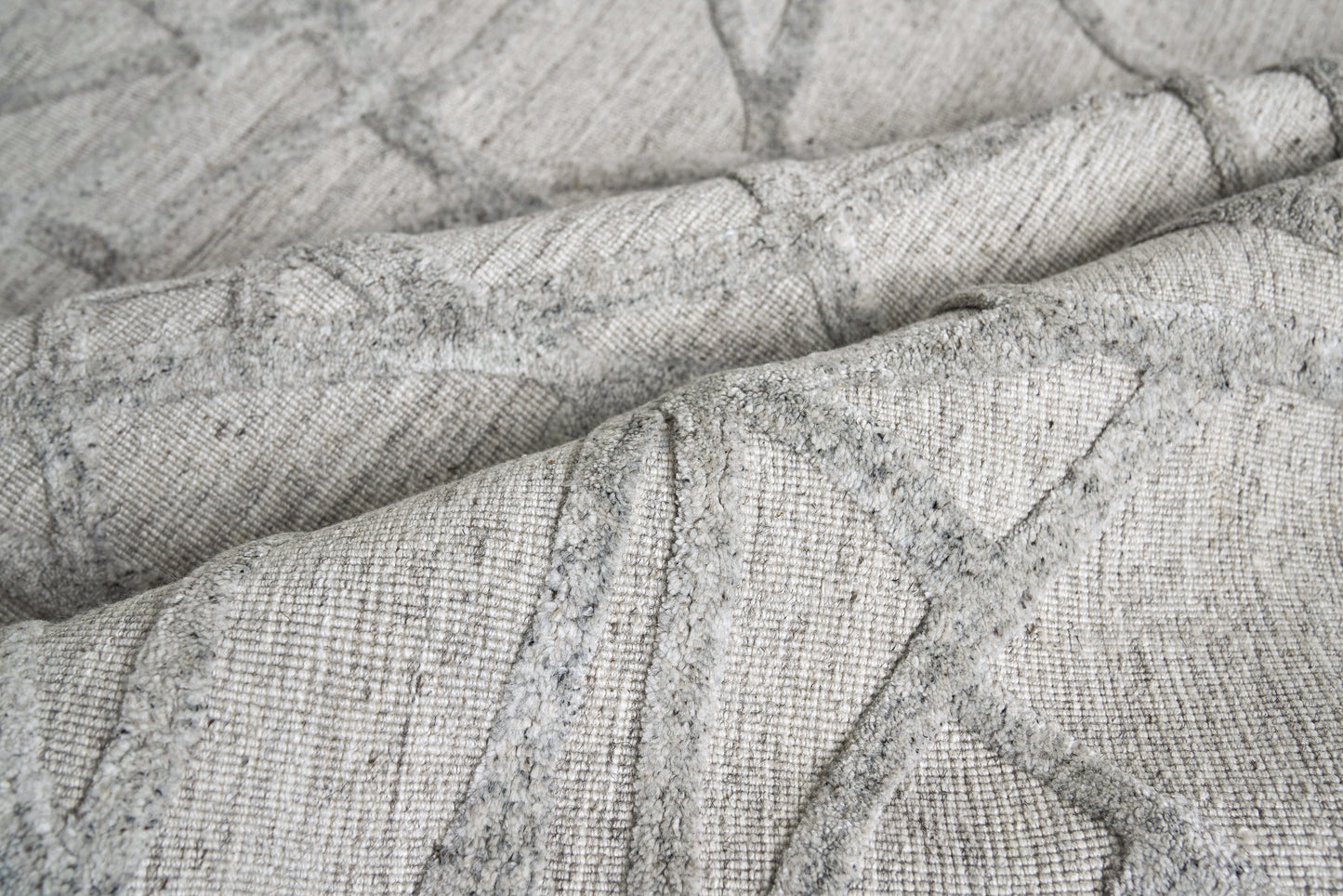 Soft grey woven fabric with a subtle geometric quilted pattern and textured weave.